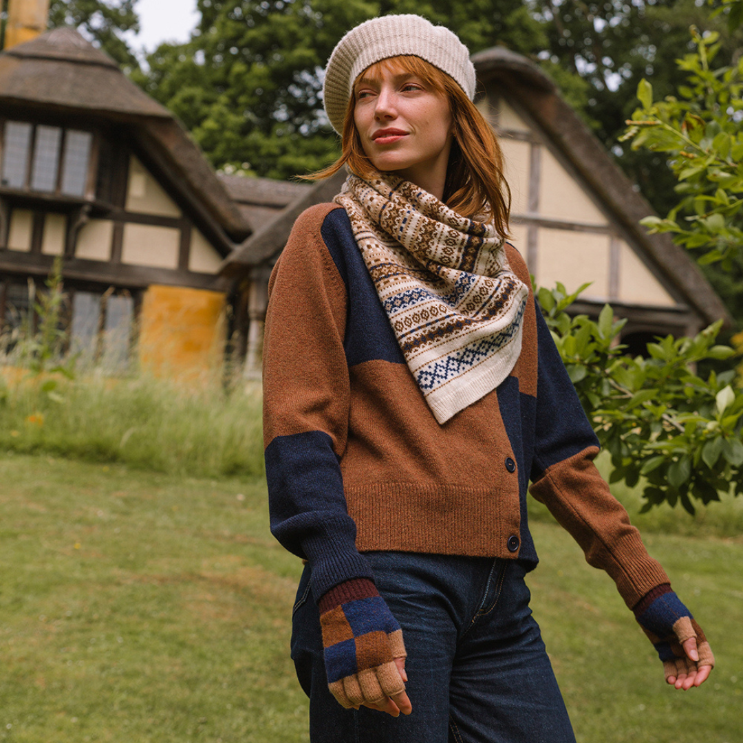 Woman wearing a patterned scarf and colorful sweater in front of a traditional building.