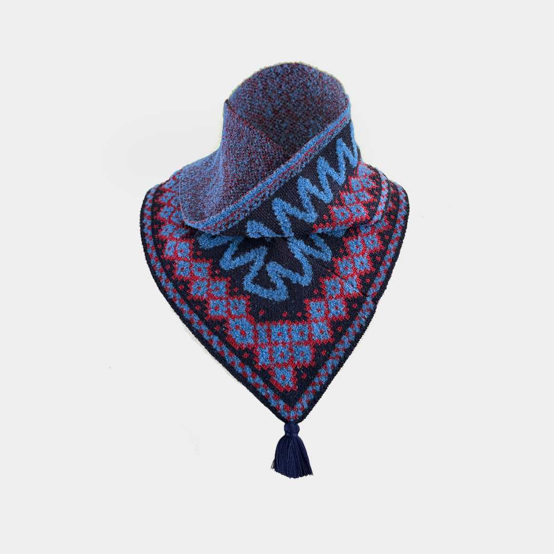 A knitted bandana-style neck warmer with a tassel, featuring a dark navy base with red and light blue geometric patterns and blue wavy accents, displayed on a light gray background.