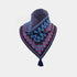 A knitted bandana-style neck warmer with a tassel, featuring a dark navy base with red and light blue geometric patterns and blue wavy accents, displayed on a light gray background.