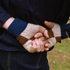Two pairs of hands holding each other, wearing checkered fingerless gloves.