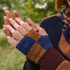 Pair of checkered fingerless gloves held by a person outdoors.