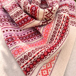 Close-up of a patterned scarf with red, pink, and white colors on a light gray background.