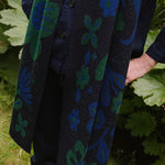 woman in a garden wearing a dark blue scarf with blue and green botanical patterns.
