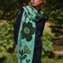 Person wearing a green floral-patterned scarf in a natural setting