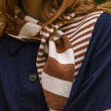 Close-up of a person wearing a brown and white striped scarf with a blue jacket.