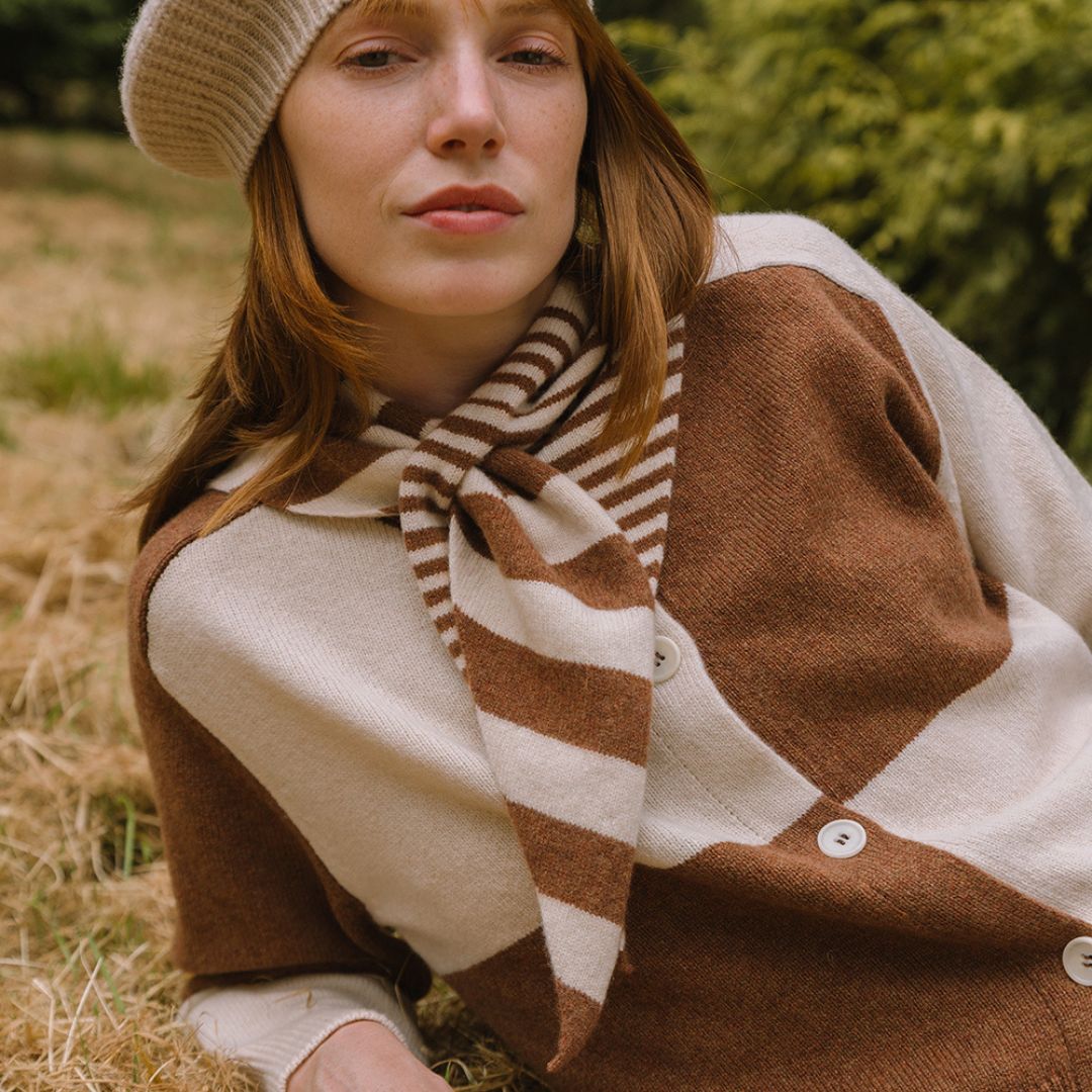 Woman wearing a brown and beige striped scarf in a natural setting