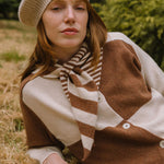 Woman wearing a brown and beige striped scarf in a natural setting