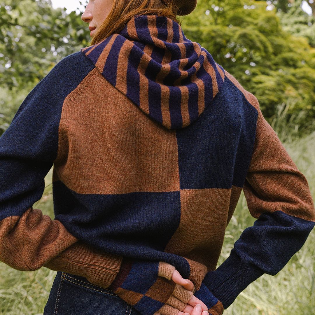 Person wearing a striped scarf with blue and brown pattern outdoors.