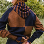 Person wearing a striped scarf with blue and brown pattern outdoors.