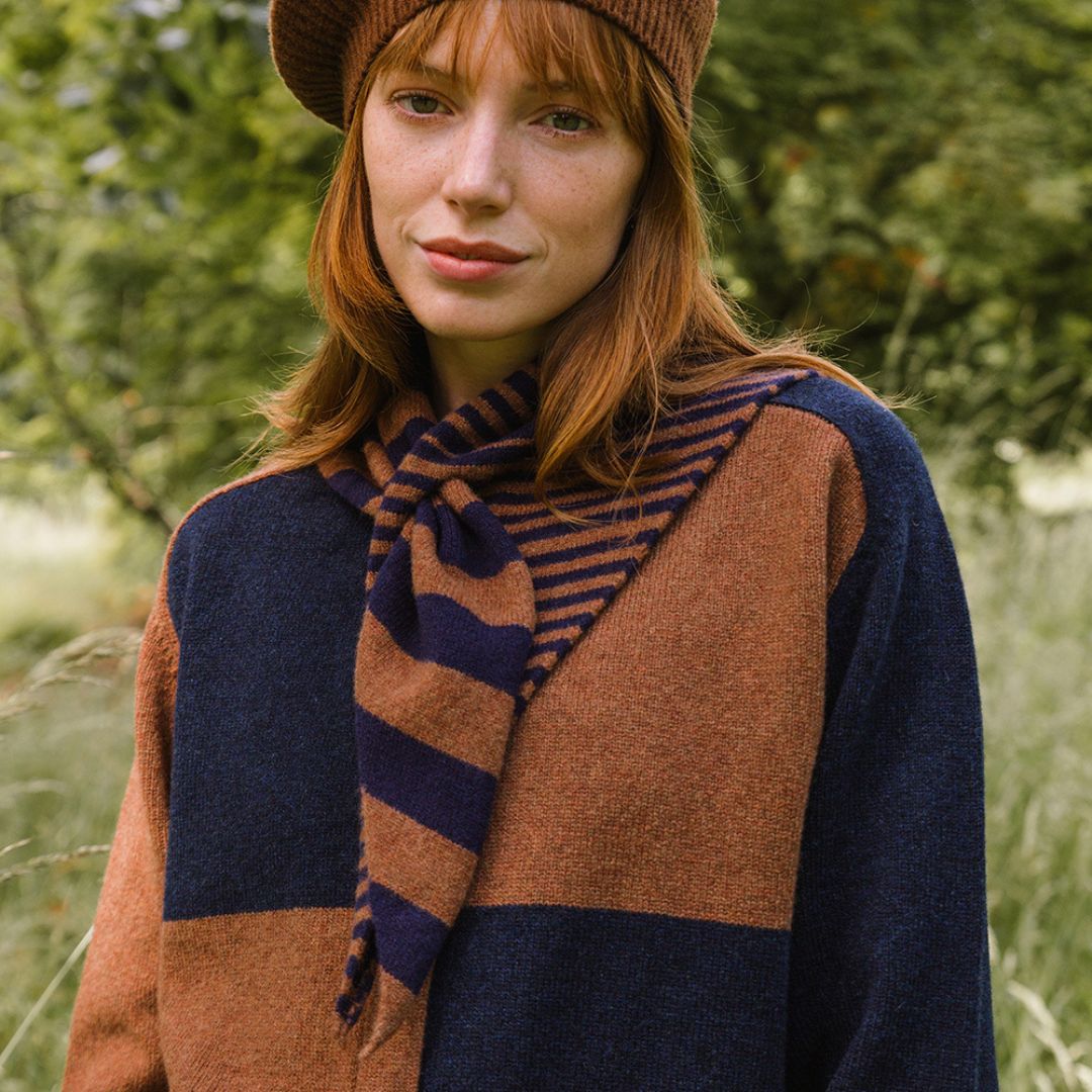 Woman wearing a brown and navy striped scarf in a natural setting