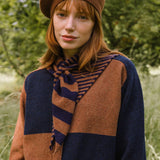 Woman wearing a brown and navy striped scarf in a natural setting