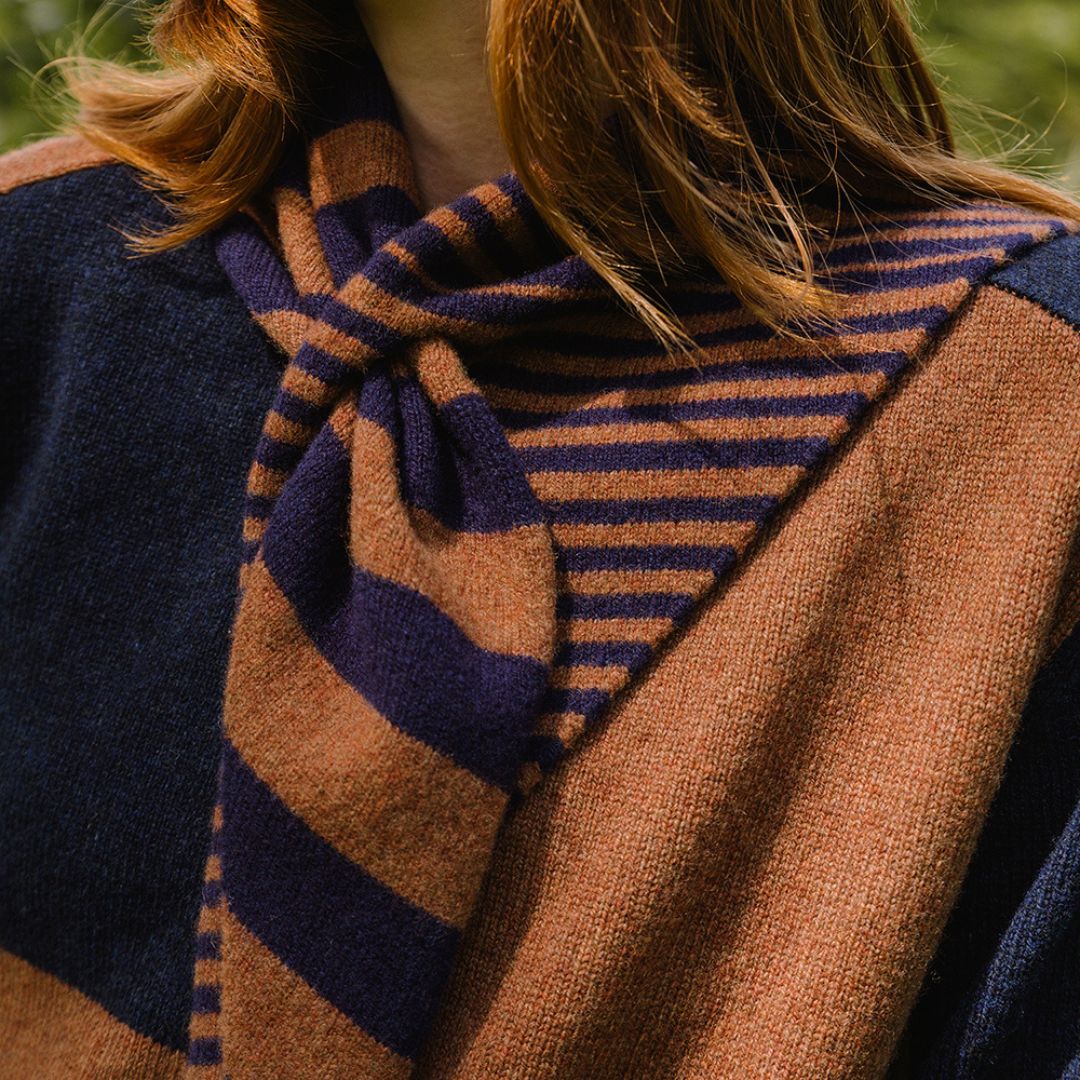 Close-up of a person wearing a striped scarf with a blurred natural background