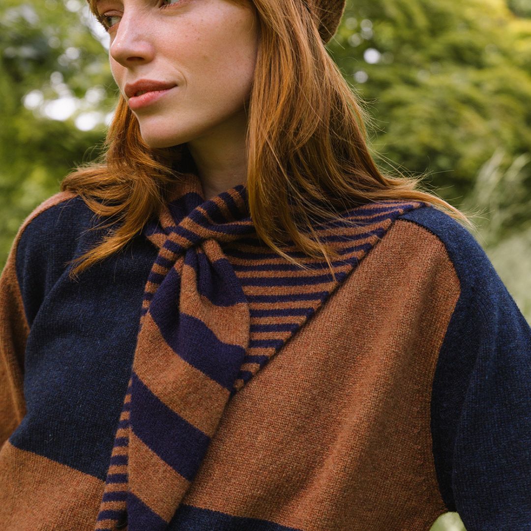 Woman wearing a brown and blue striped scarf with a blurred green background