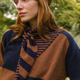 Woman wearing a brown and blue striped scarf with a blurred green background