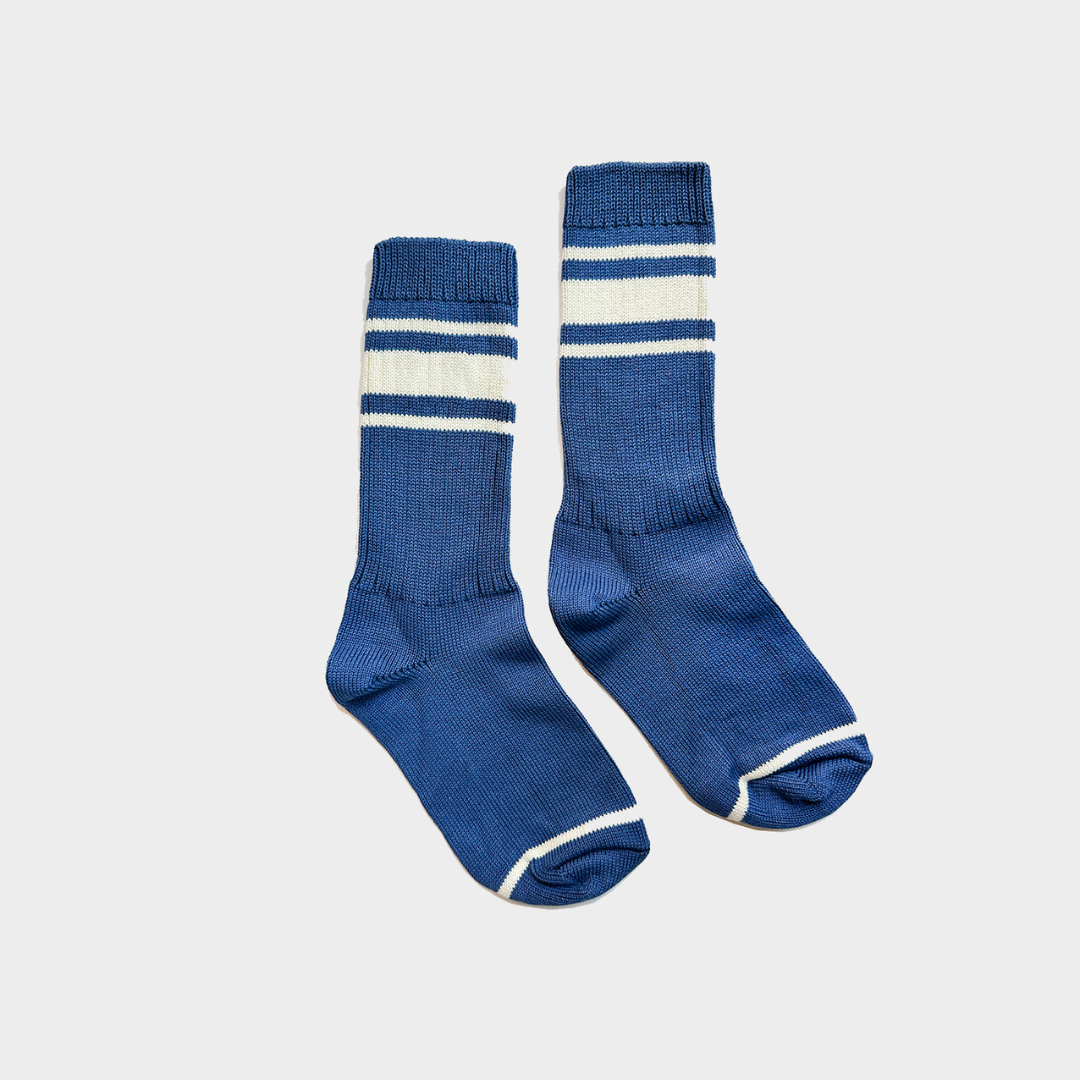 A pair of blue crew socks with white stripes near the top and white trim on the toes, displayed against a light gray background.