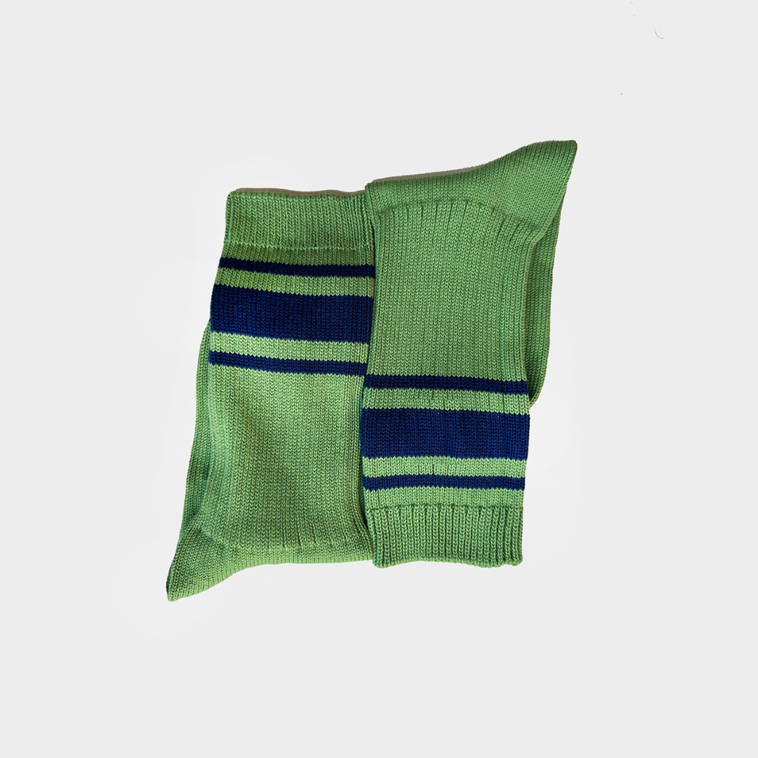 A pair of green knit crew socks with navy blue and white horizontal stripes near the cuff, displayed against a light gray background.
