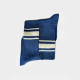 A pair of navy blue knit socks with cream and white horizontal stripes, folded neatly on a light gray background.