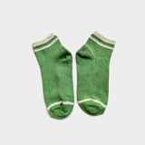 A pair of green ribbed knit ankle socks with white stripes at the ribbed cuffs and toes, displayed against a light gray background.
