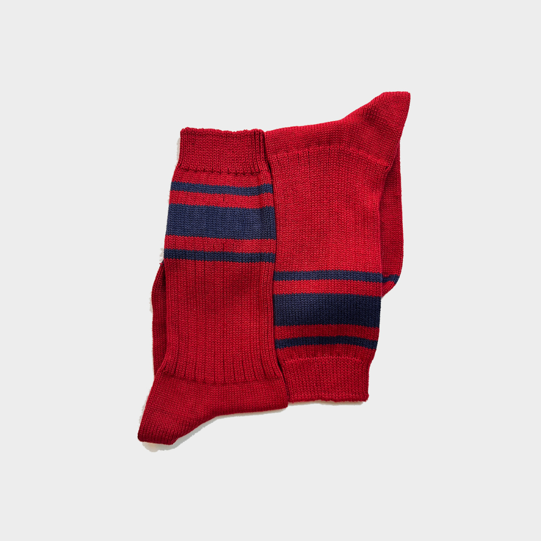 A pair of red knit crew socks with navy blue horizontal stripes, displayed against a light gray background.