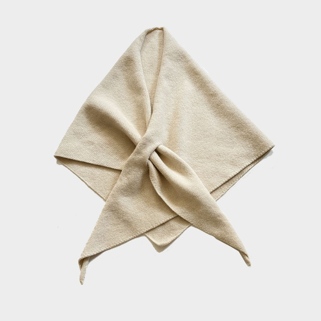 A light beige textured fabric scarf tied in a neat knot, displayed against a solid light gray background.