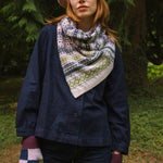 woollen twisted snood in light pinks, greens and blues worn by model in the woods.