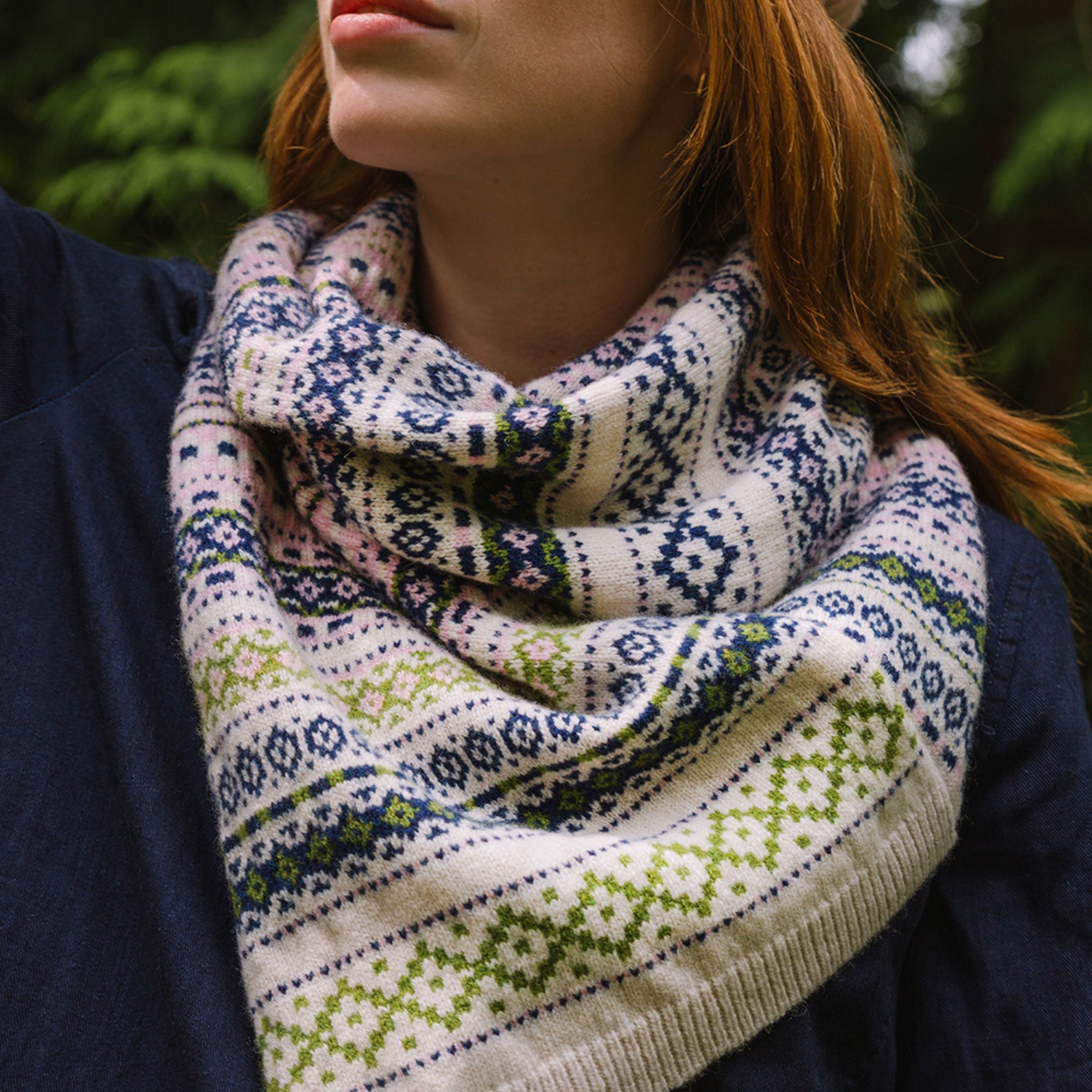 woollen twisted snood in light pinks, greens and blues worn by model in the woods.
