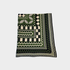 A folded patterned textile blanket, featuring a geometric design in olive green, black, and cream on a light gray background.