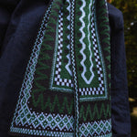 Person wearing a patterned scarf with green, black, and white design.