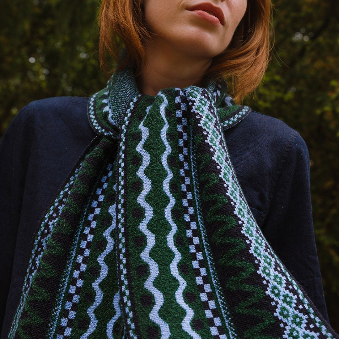 Person wearing a patterned scarf with a blurred natural background