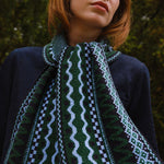 Person wearing a patterned scarf with a blurred natural background