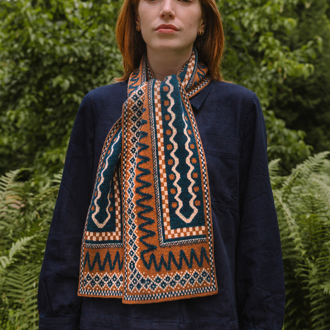 Person wearing a patterned scarf in front of green foliage