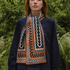Person wearing a patterned scarf in front of green foliage