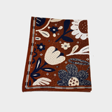 A knitted blanket featuring a retro floral pattern in brown, cream, and navy blue on a light gray background.