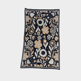 A rectangular blanket featuring a dense floral and botanical pattern on a dark navy background, with cream, beige, and light brown flowers and leaves, shown flat against a light gray background.