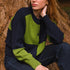 Person wearing a navy and green cardigan sitting against a tree.