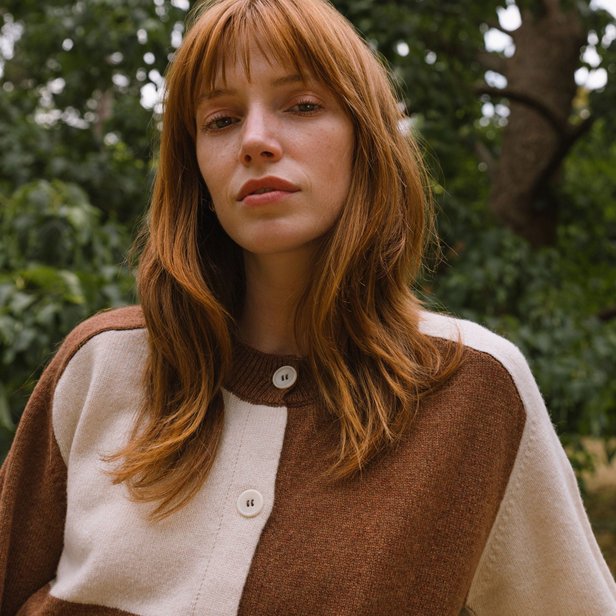 model in the woods wearing check cardigan in cream and brown.