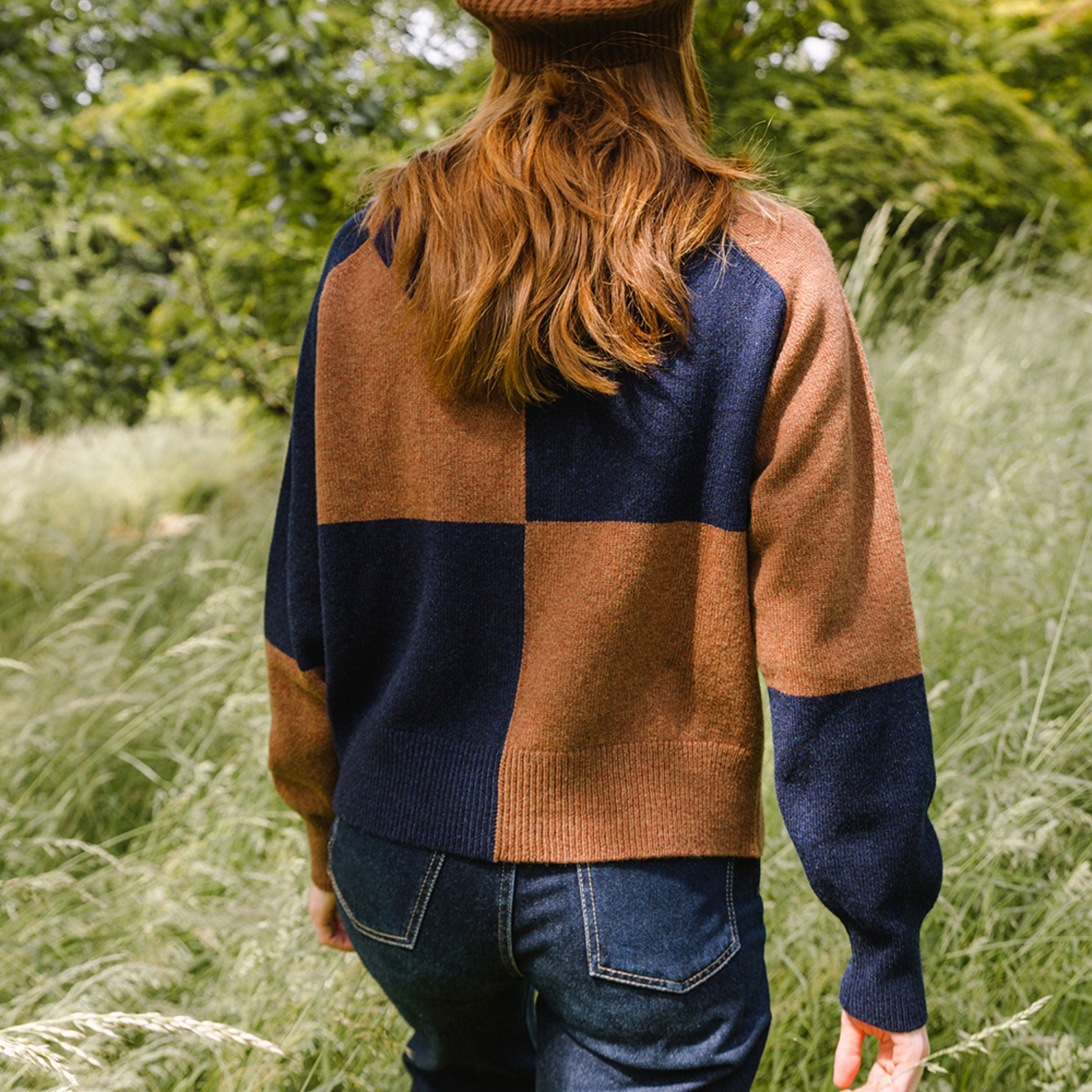 Person wearing a checkered cardigan in a natural setting