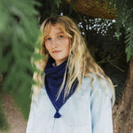 A lady in a woodland wearing a blue cable knit scarf.