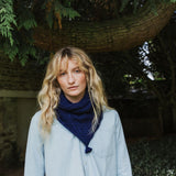 A lady standing under a tree wearing a blue scarf.