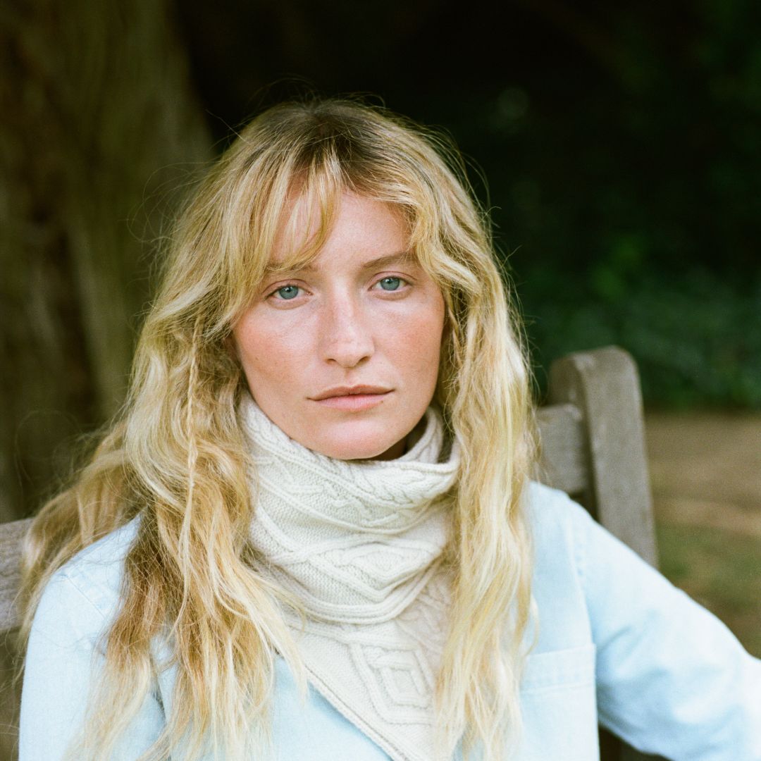 Lady wearing a cream cable knit scarf.