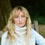 Lady wearing a cream cable knit scarf.