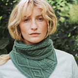 a close up of a woman wearing a green cable knit scarf.