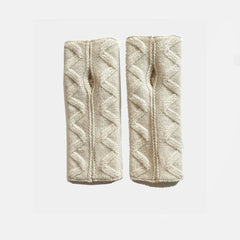 A pair of cream-colored cable-knit wrist warmers with a textured chevron pattern, displayed side-by-side on a light gray background.