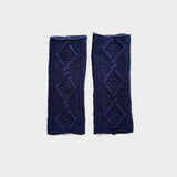 A pair of navy blue cable-knit wrist warmers with diamond patterns, displayed flat against a light gray background.r