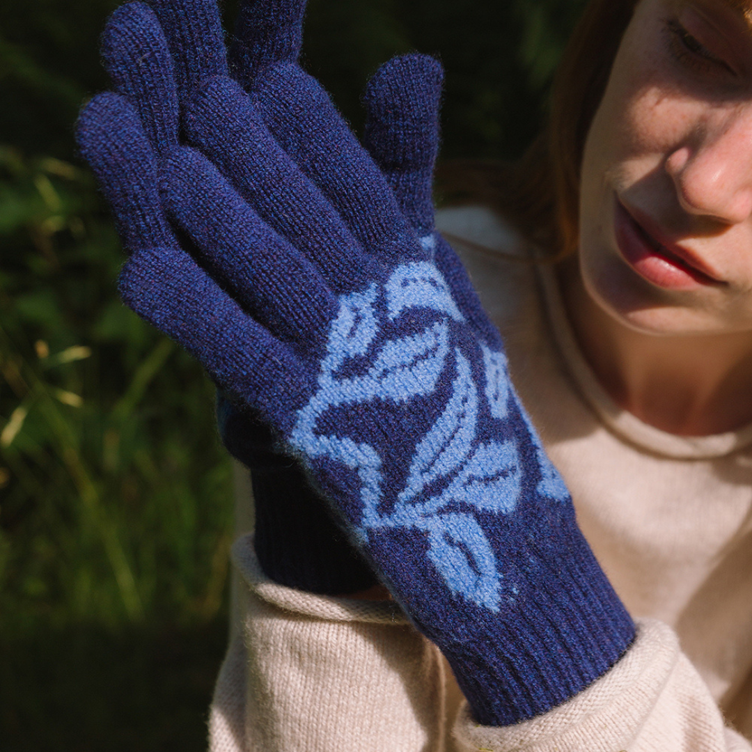 Person wearing blue knitted gloves with a floral pattern outdoors