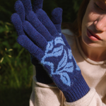 Person wearing blue knitted gloves with a floral pattern outdoors