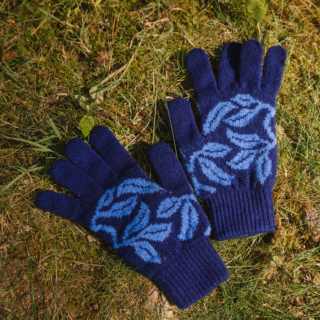 Pair of blue gloves with leaf pattern on grass