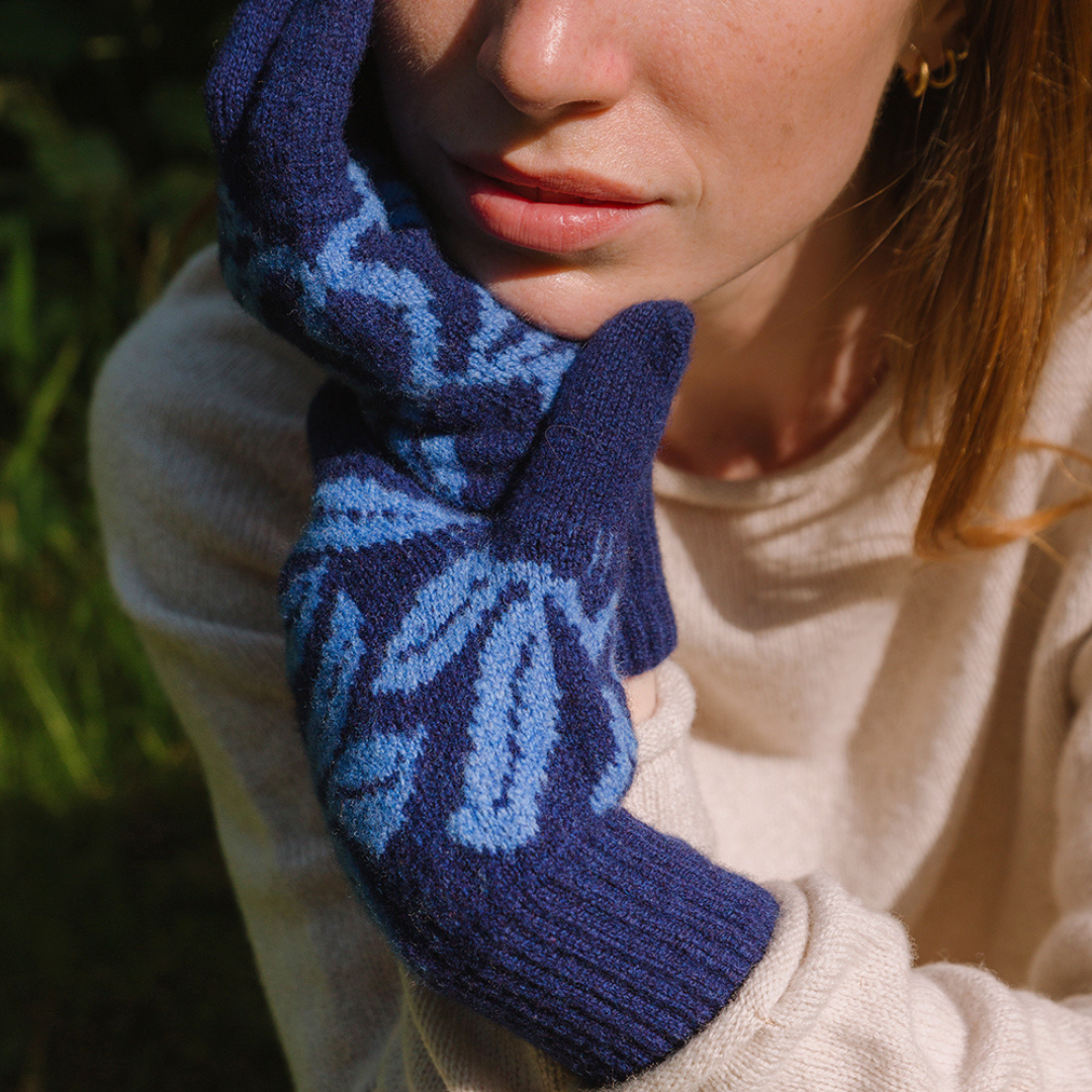 Person wearing blue patterned gloves with a blurred natural background