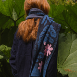 Person wearing a dark blue floral-patterned scarf in a garden setting