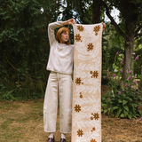 Person holding a long floral-patterned scarf in a garden setting